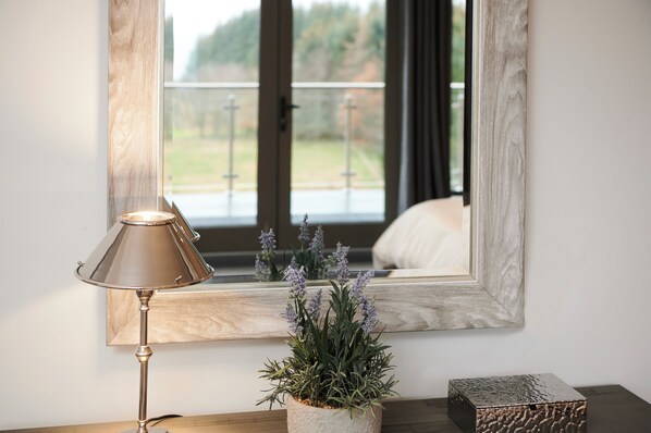 A room with a large mirror, a lamp, and a potted plant.