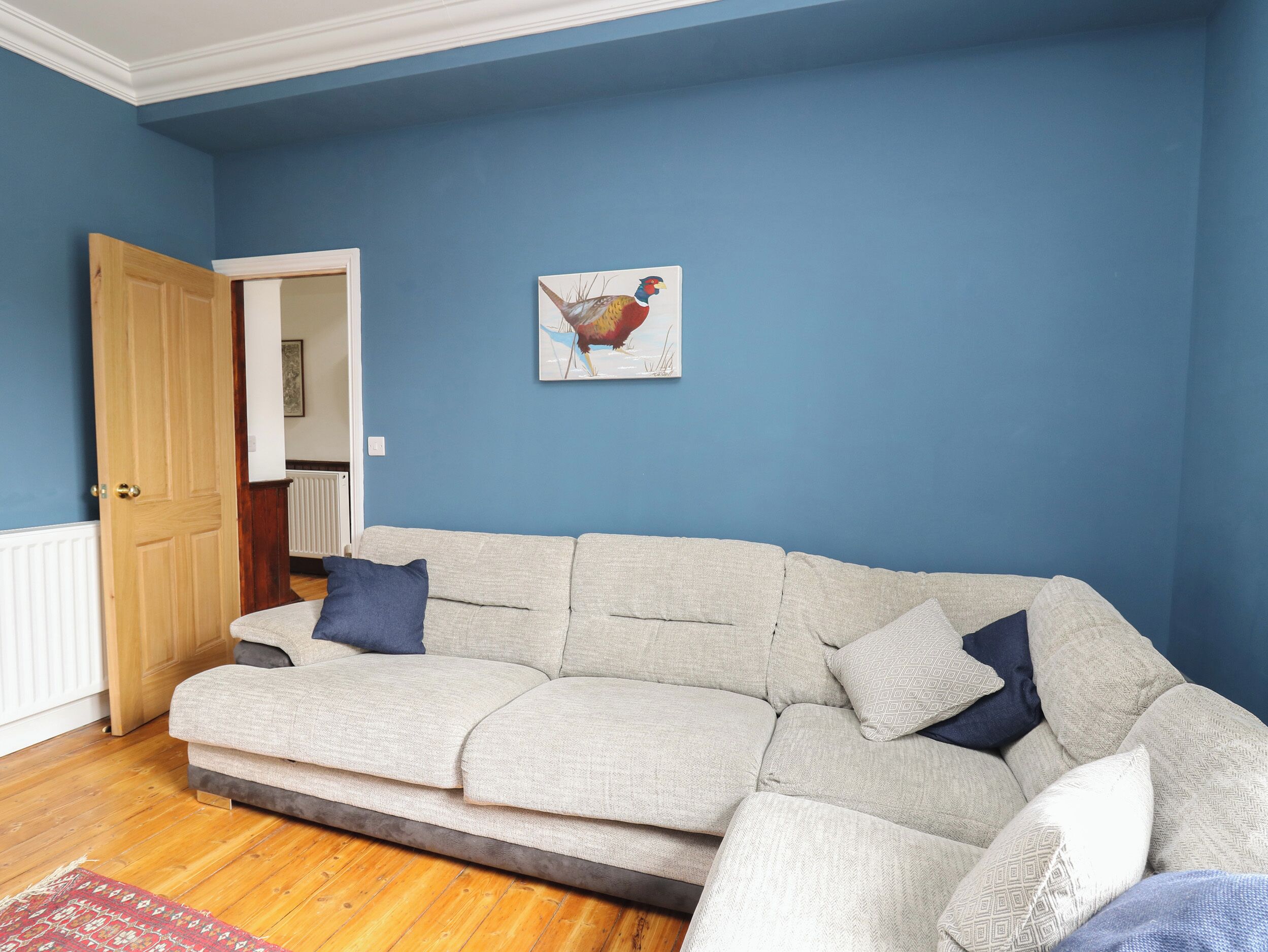 A living room with a beige sofa, a blue wall, and a wooden door.