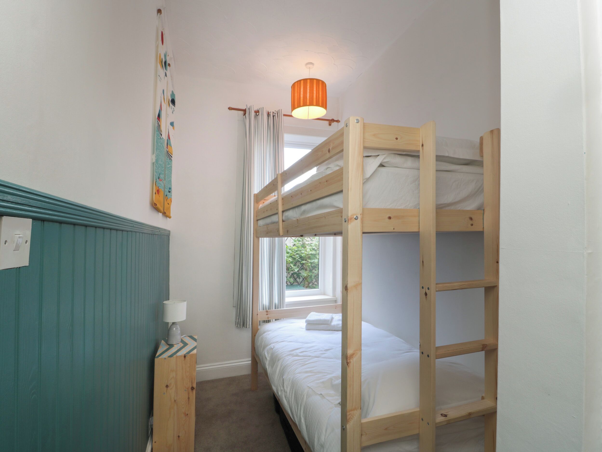 A bunk bed room with a window, a lamp, and a wall-mounted light fixture.