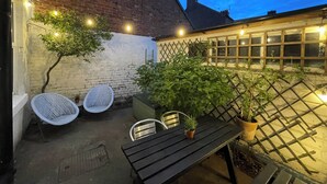 A patio with a table and chairs, surrounded by potted plants and a brick wall. - Limpet Lodge (North Shields)