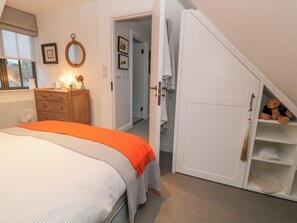 Une chambre à coucher avec un lit, une commode et un ours en peluche posé sur une étagère.