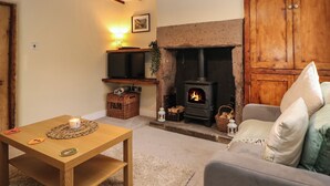 Ein gemütliches Wohnzimmer mit Kamin, Fernseher und bequemer Couch.