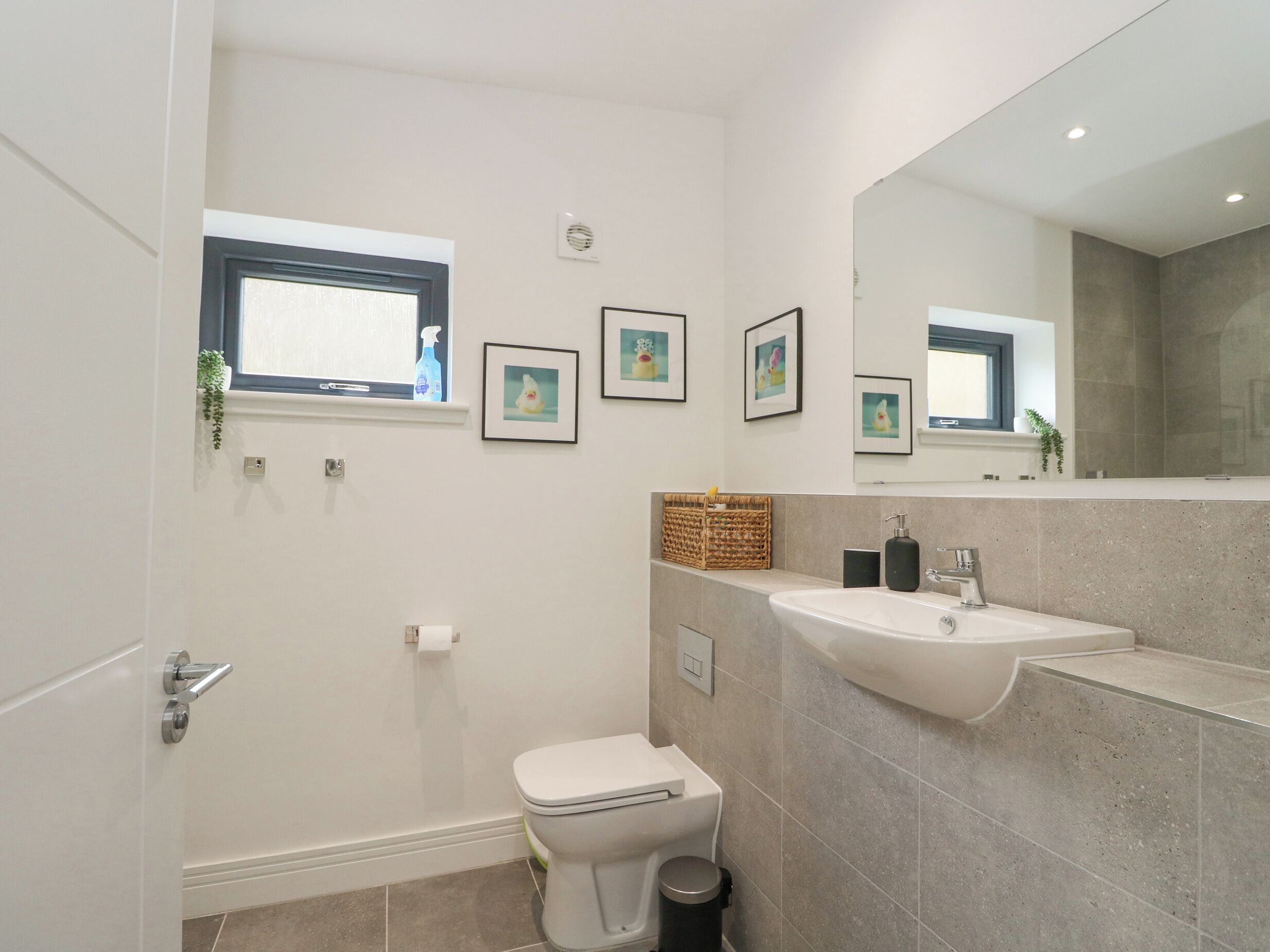 A modern bathroom with a toilet, sink, and a large mirror.