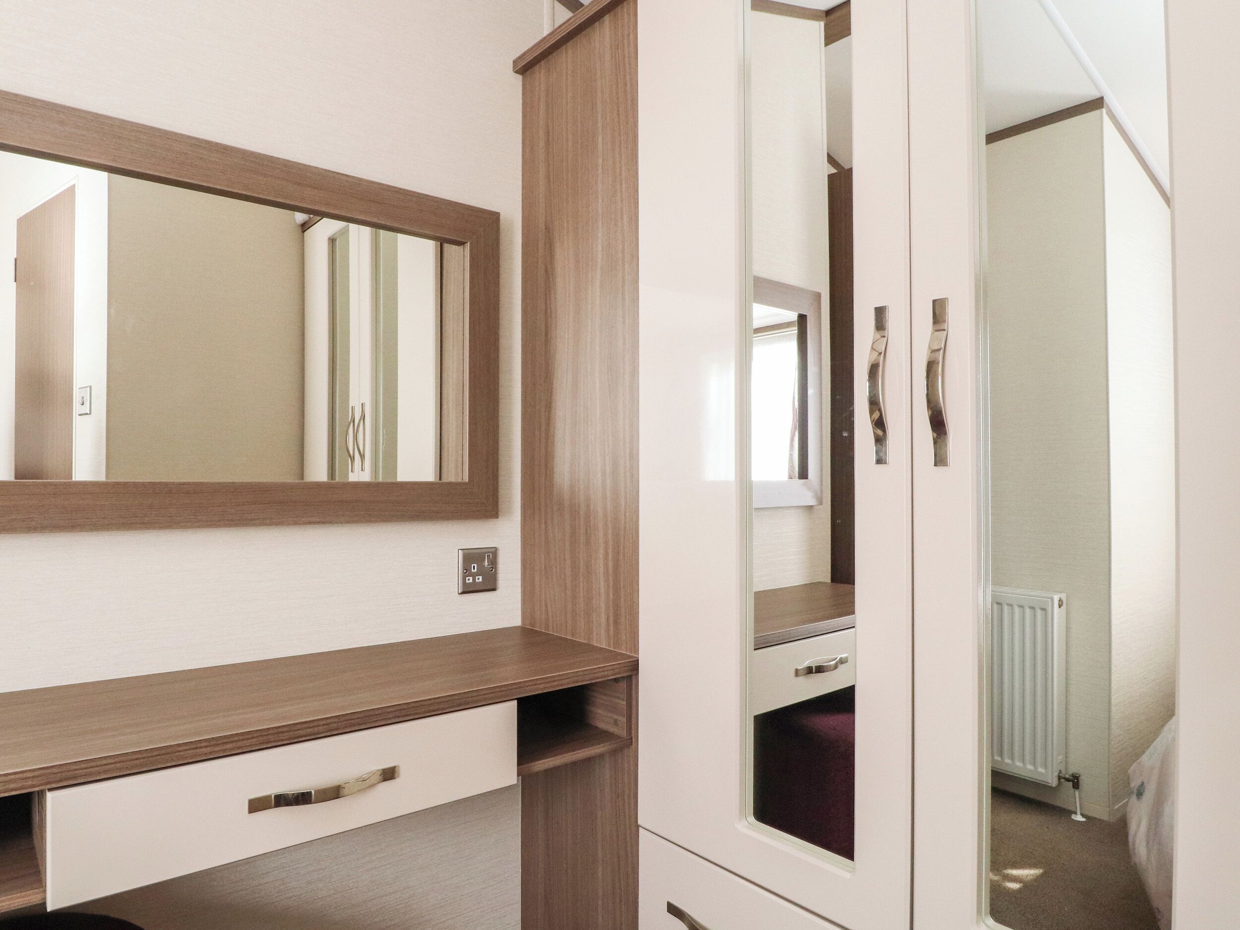 Un dormitorio con un aparador de madera, un espejo y un radiador.