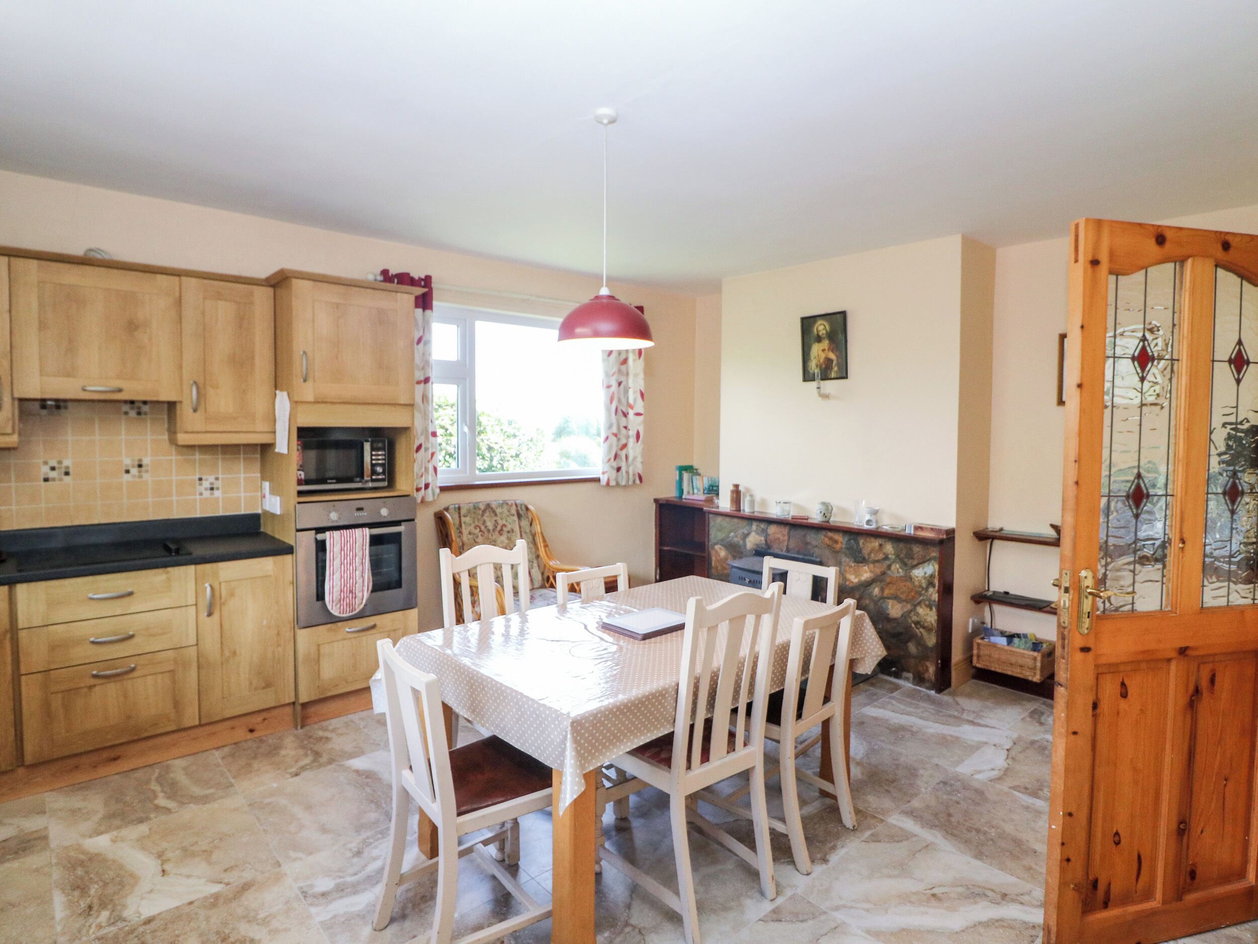 Une cuisine avec des meubles de rangement en bois, un four à micro-ondes et une table à manger avec des chaises.