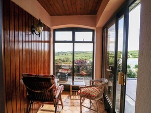 A room with a wooden ceiling and walls, a large window, and two wicker chairs. - An Radharc Álainn (Rosscarbery)