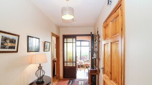 A hallway with a wooden door, a lamp, and framed pictures on the wall. - An Radharc Álainn (Rosscarbery)