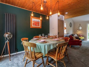 A dining area with a table set for four, wooden chairs, a green checkered tablecloth, and a framed picture on the wall. - The Sail Loft (Y Felinheli)