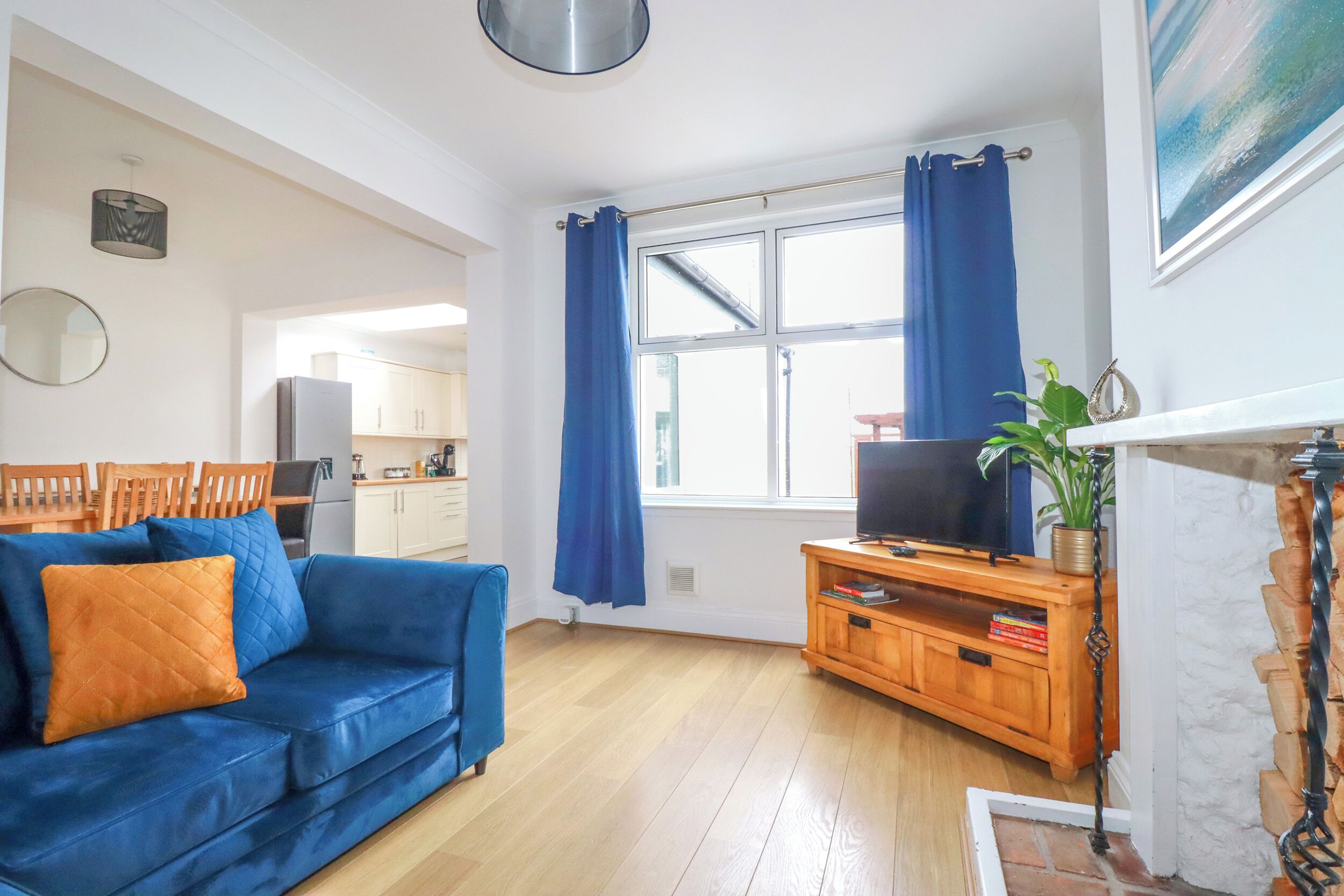 A living room with a blue sofa, wooden entertainment unit, and a television.