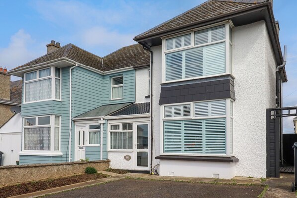 A two-story residential building with a bay window and a door with a number plaque.