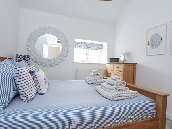 A bedroom with a bed, a dresser, a mirror, and a window. - Gwel-y-rhos (Llanfairpwllgwyngyll)