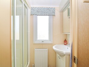A bathroom with a window, a radiator, a sink, and a mirror. - Cae Gog (Amlwch)