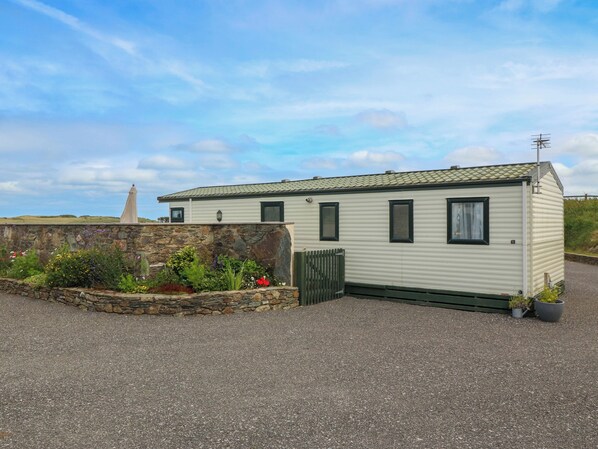A mobile home with a stone wall and garden in front. - Cae Gog (Amlwch)