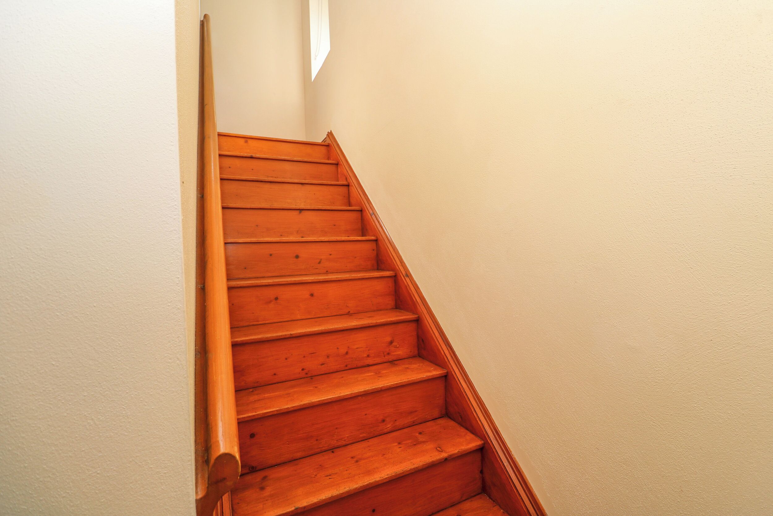 Un escalier en bois, doté d’une rampe, menant à un palier.