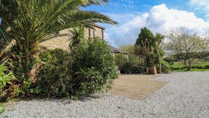 A stone building with a gravel driveway, surrounded by lush greenery and palm trees. - The Granary (Penzance)