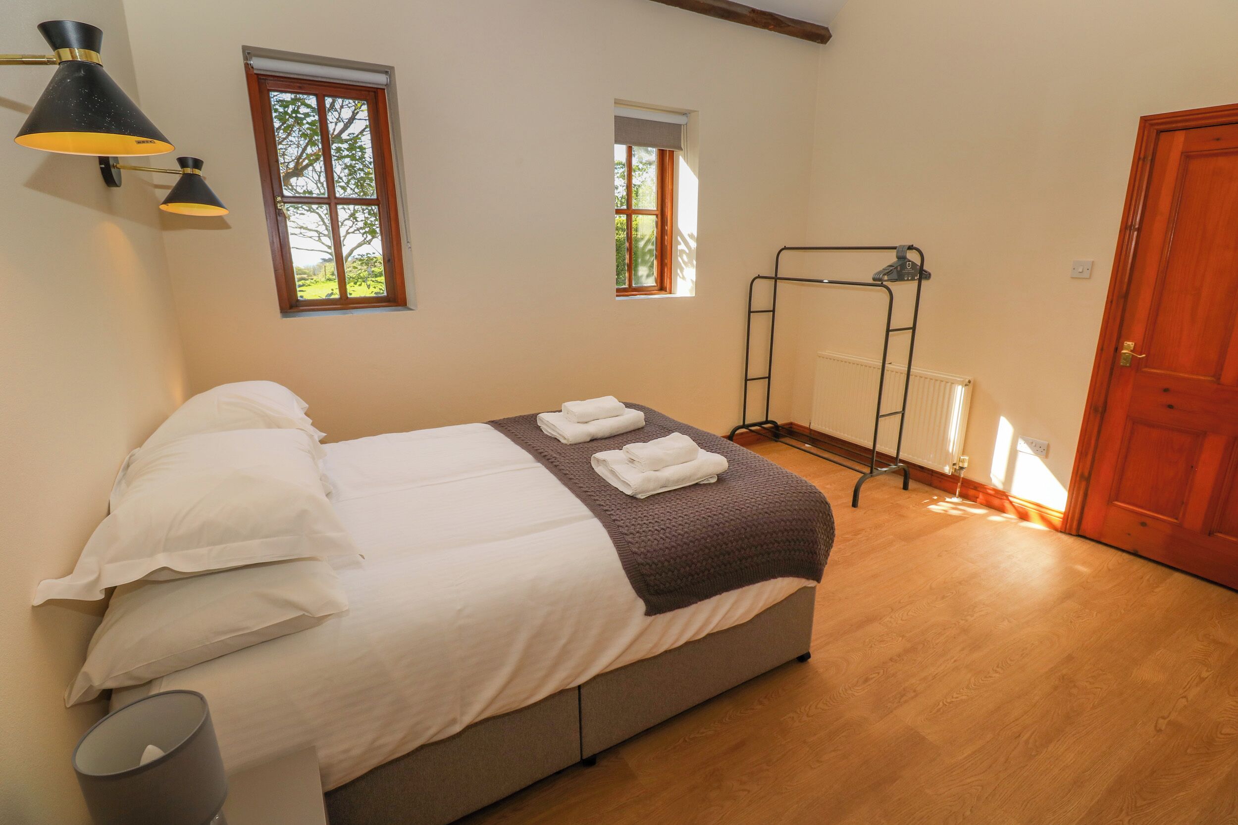 A bedroom with a bed, two windows, a radiator, and a door.