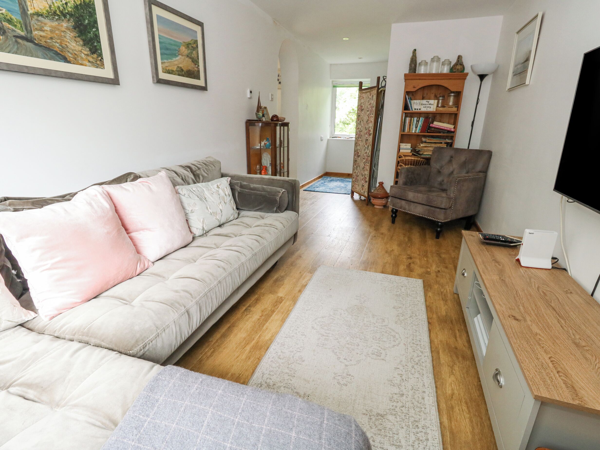 A living room with a sofa, a wooden cabinet, a TV, and a bookshelf.