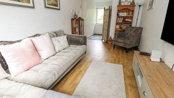A living room with a sofa, a wooden cabinet, a TV, and a bookshelf.