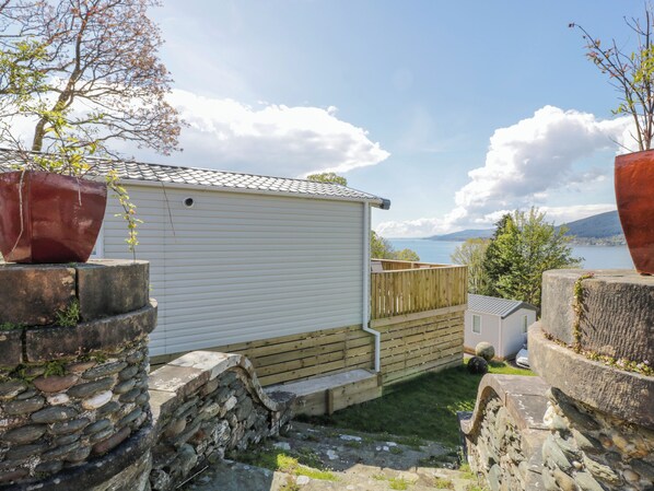 A white mobile home with a wooden deck and a stone wall. - 11A Mansion View (Helensburgh)