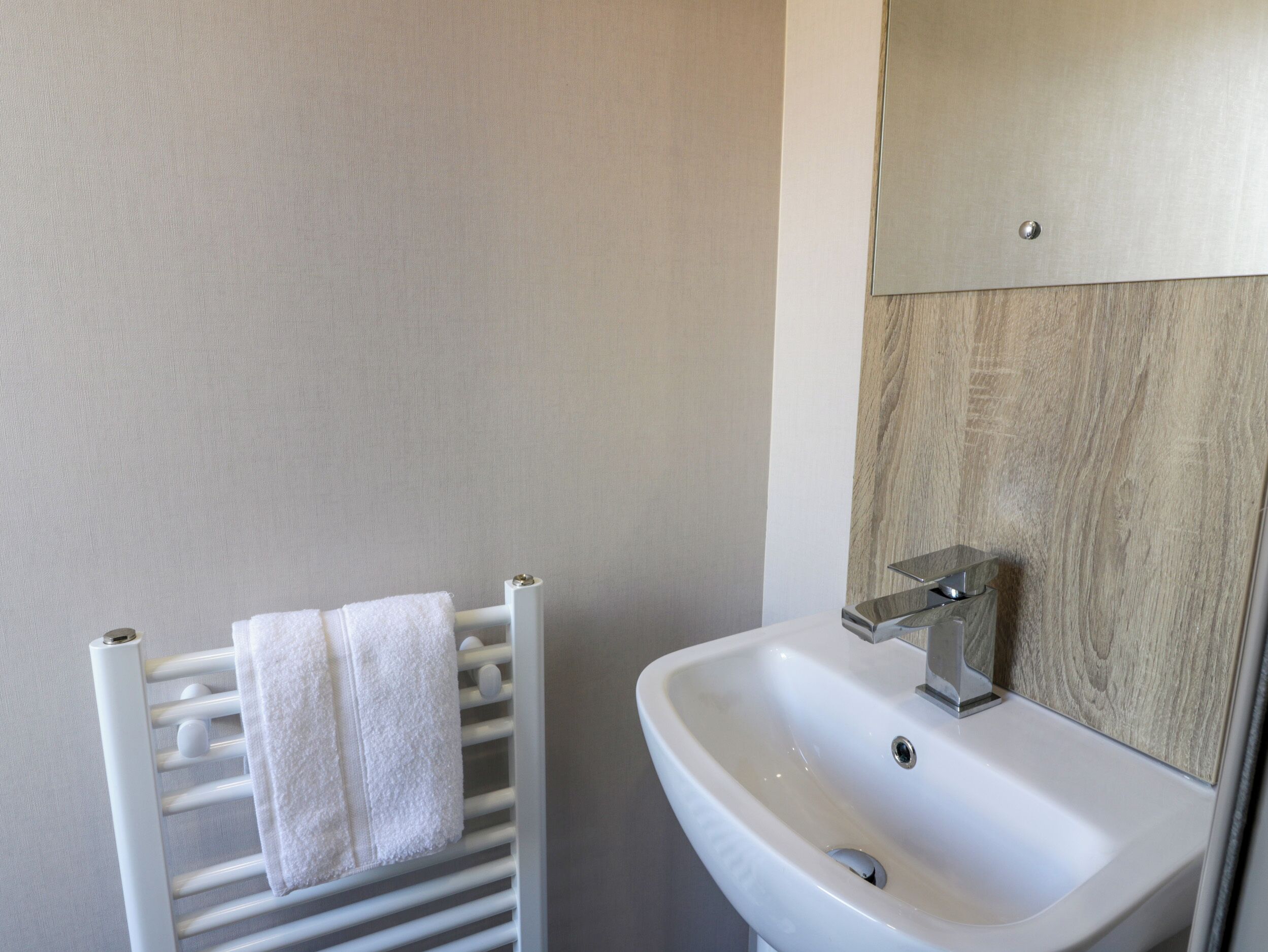 A bathroom with a white towel rack, a white sink, and a wooden panel wall.