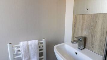 A bathroom with a white towel rack, a white sink, and a wooden panel wall.