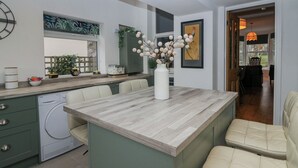 Een moderne keuken met een centraal eiland, ingebouwde apparatuur en een eethoek met stoelen.