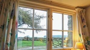 Ein Zimmer mit einem großen Fenster, Vorhängen und einer Tischlampe.
