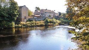 Een rivier met een stenen gebouw en huizen op de achtergrond.