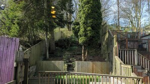 A wooden deck with a stone pathway leading to a wooden staircase. - 69 Main Street (Keighley)