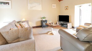 A living room with a sofa, a coffee table, a TV, and a wooden ceiling. - Dove Cottage (Leek)