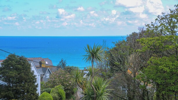 A coastal road with a view of the ocean and houses in the background. - Talland View (St Ives)