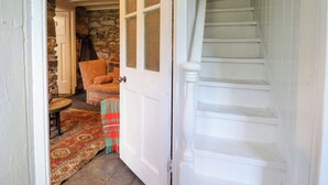 A staircase leading to a stone wall room with a patterned rug and a patterned chair. - Nyth Yr Eryr (Blaenau Ffestiniog)