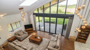 A spacious living room with a large window, a flat-screen TV, and a wooden coffee table. - Hidden Well (Bristol)