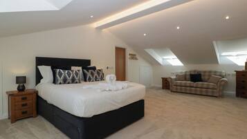 A spacious bedroom with a large bed, a sofa, and a skylight.