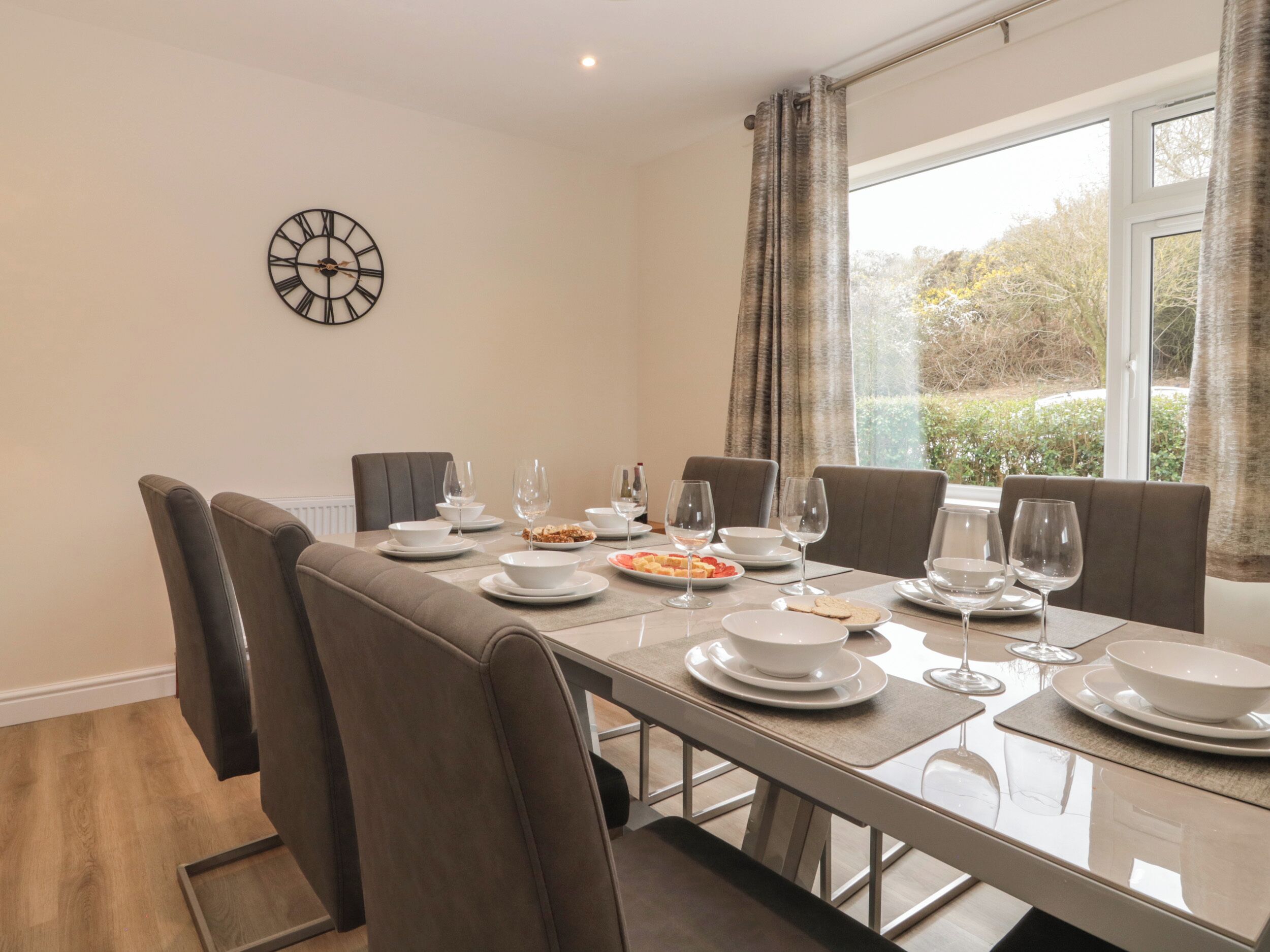 A dining area with a table set for six, including plates, bowls, and wine glasses.