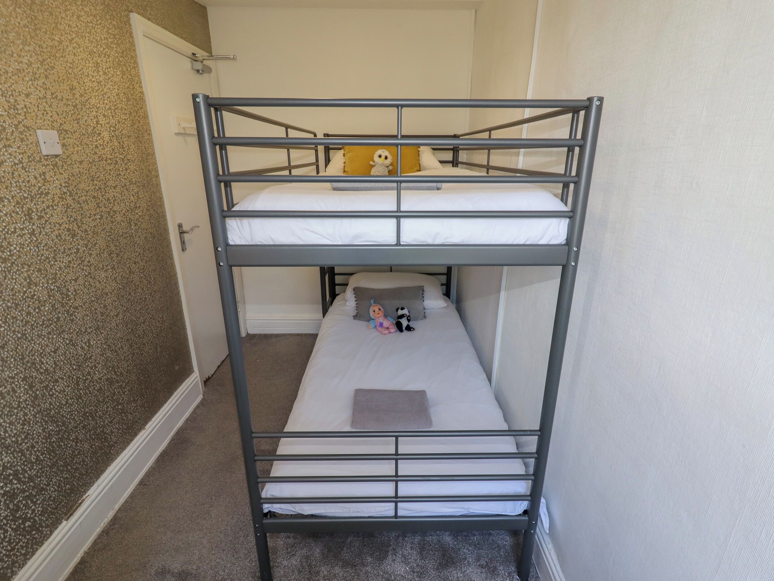 A bunk bed room with a door and a textured wall.