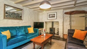 Una sala de estar con un sofá azul, una mesa de centro de madera, una chimenea de piedra y un televisor.