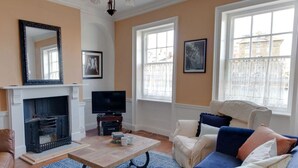 Ein Wohnzimmer mit Kamin, Sofa, Fernseher und Kunstwerken an den Wänden.