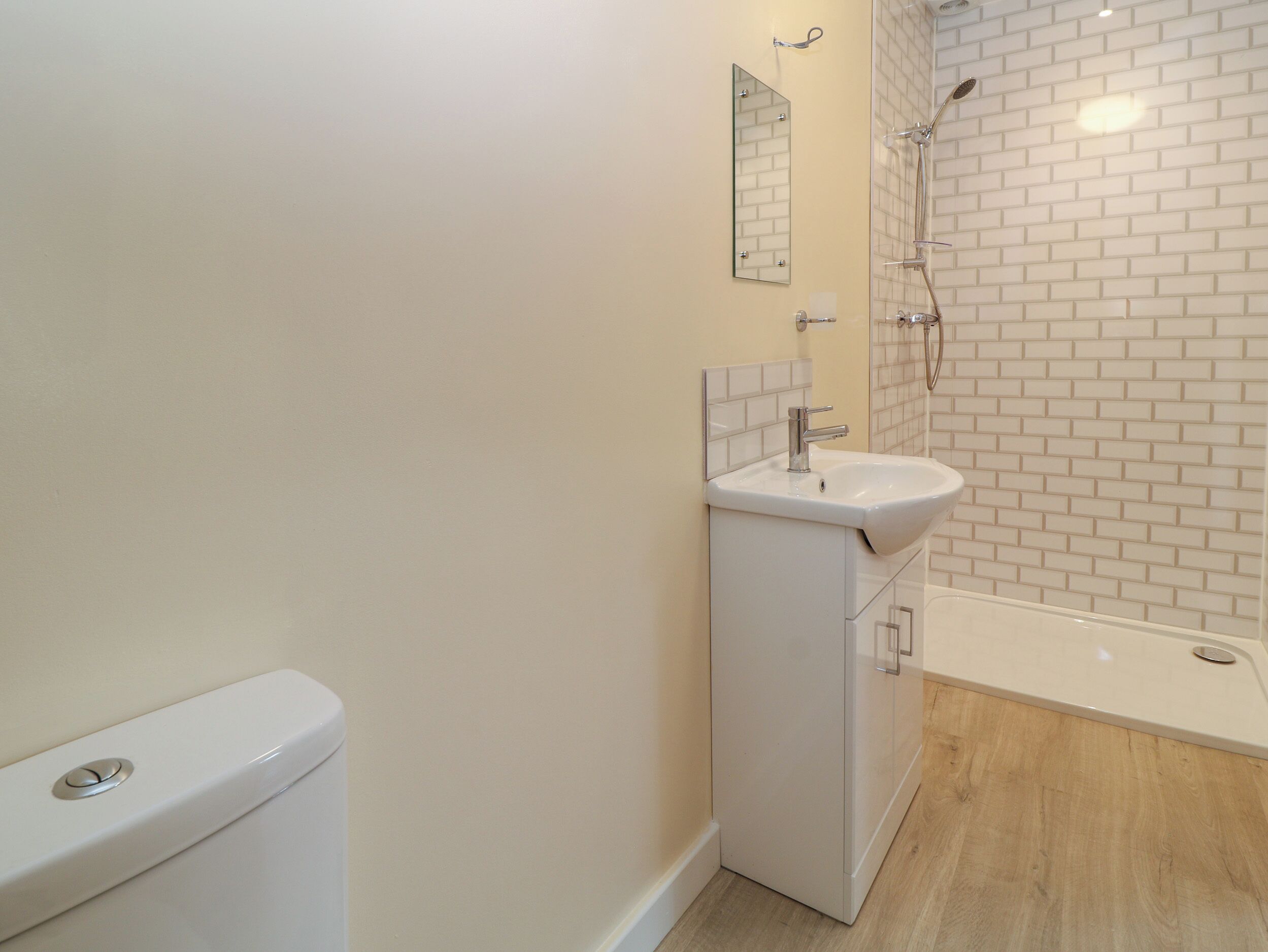 Une salle de bain avec des toilettes blanches, un lavabo et une douche.
