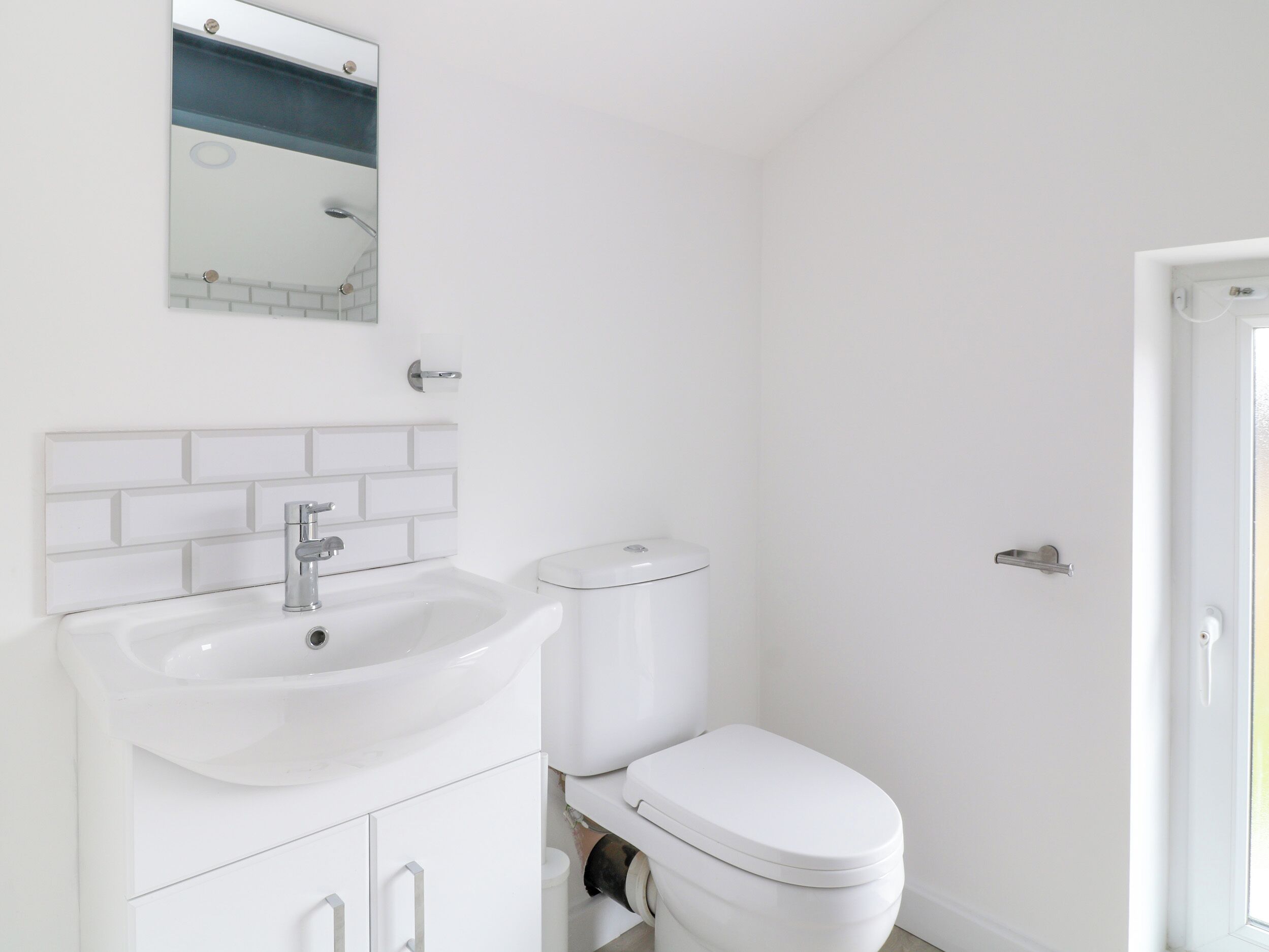 A bathroom with a white sink, a toilet, and a mirror above the sink.