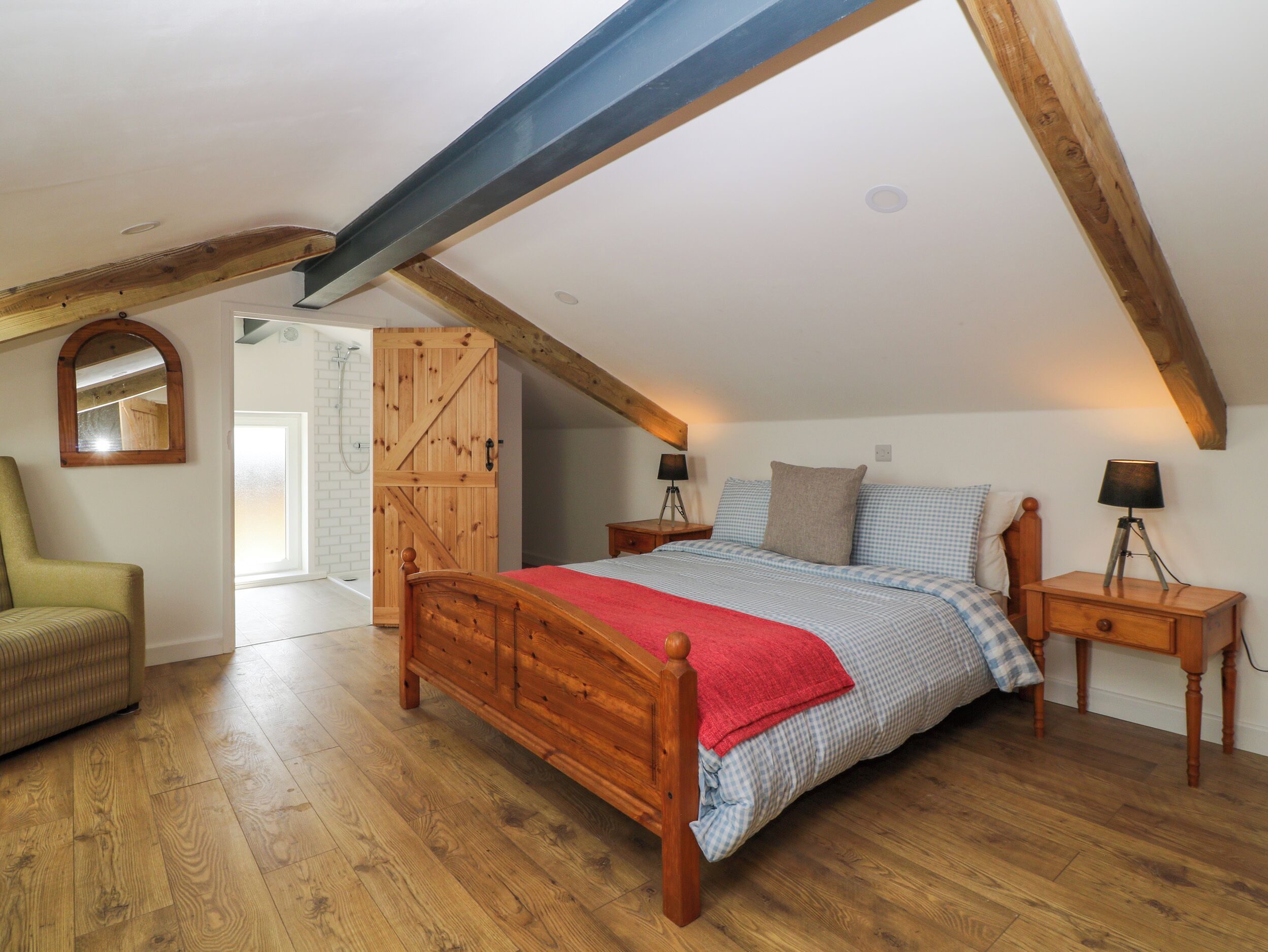 Ein Schlafzimmer mit einem hölzernen Bett, einem Schrank, einem Stuhl und einem Nachttisch mit einer Lampe.