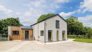 A modern two-story building with a flat roof and large windows. - Muddy Udders Dairy (Okehampton)