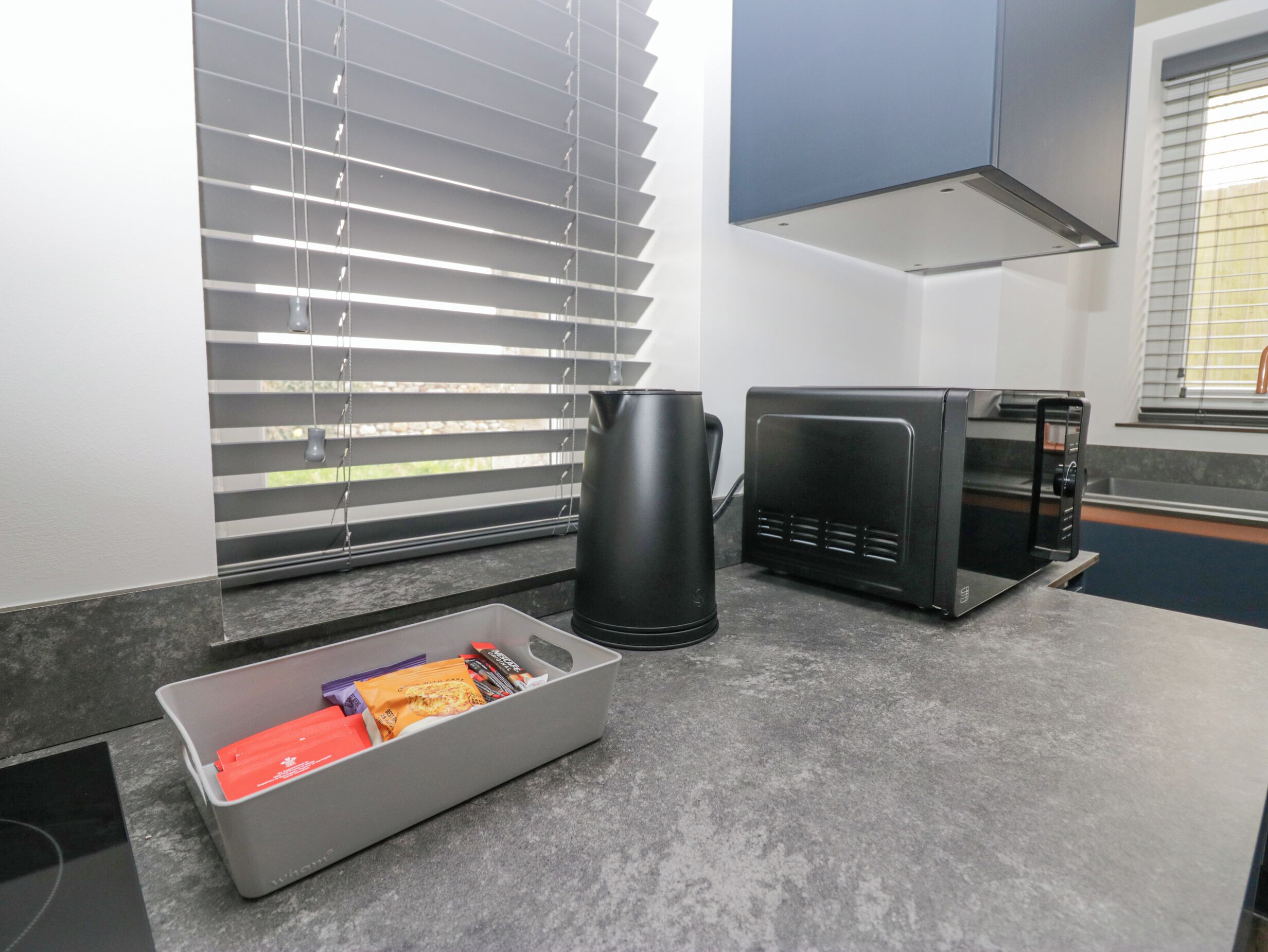 A kitchen with a coffee maker, microwave, and a tray with snacks.