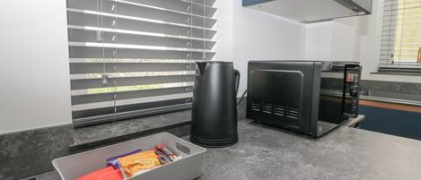 A kitchen with a coffee maker, microwave, and a tray with snacks.