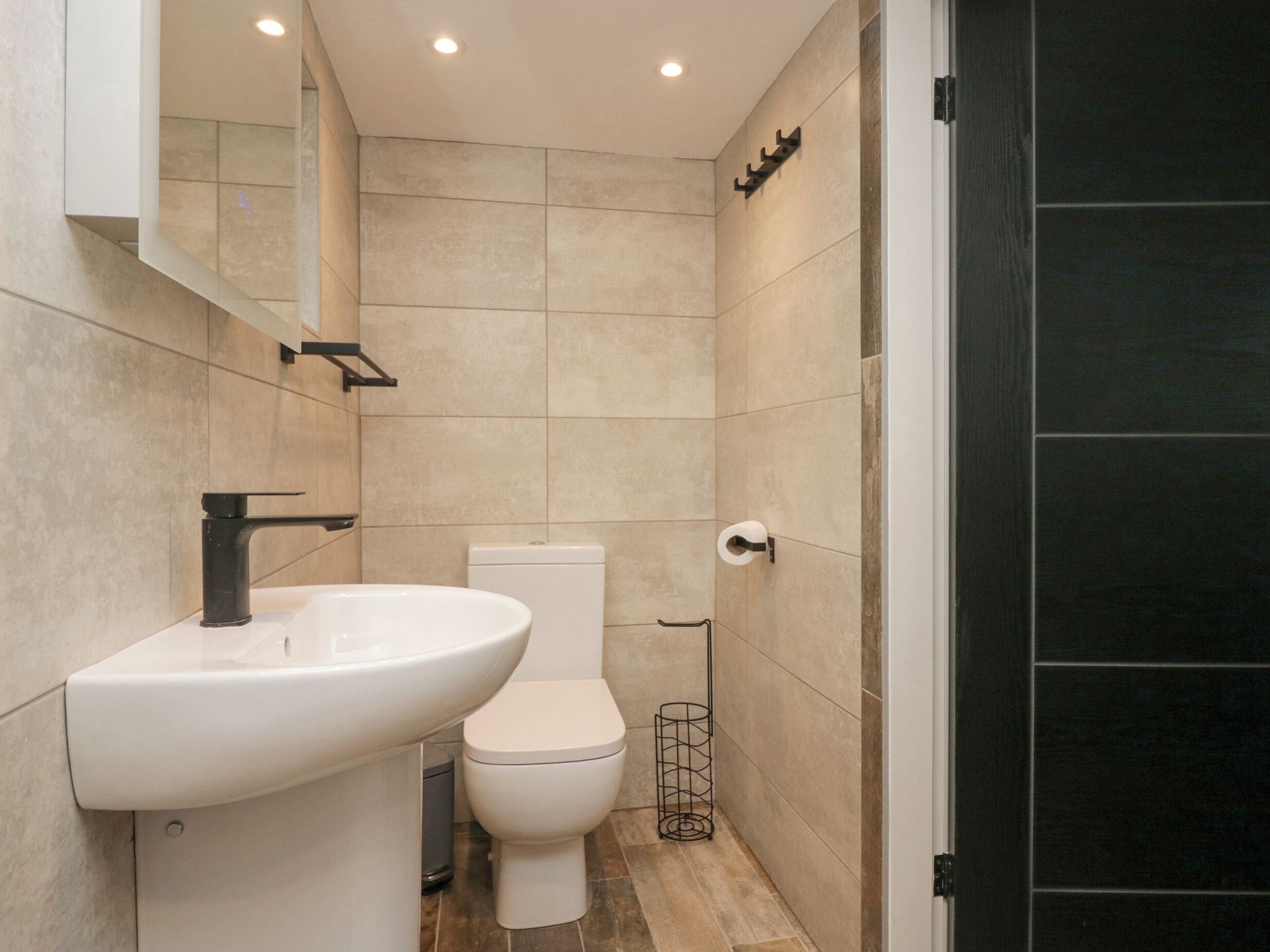 Une salle de bain moderne avec un lavabo blanc, des toilettes et un porte-serviettes noir.