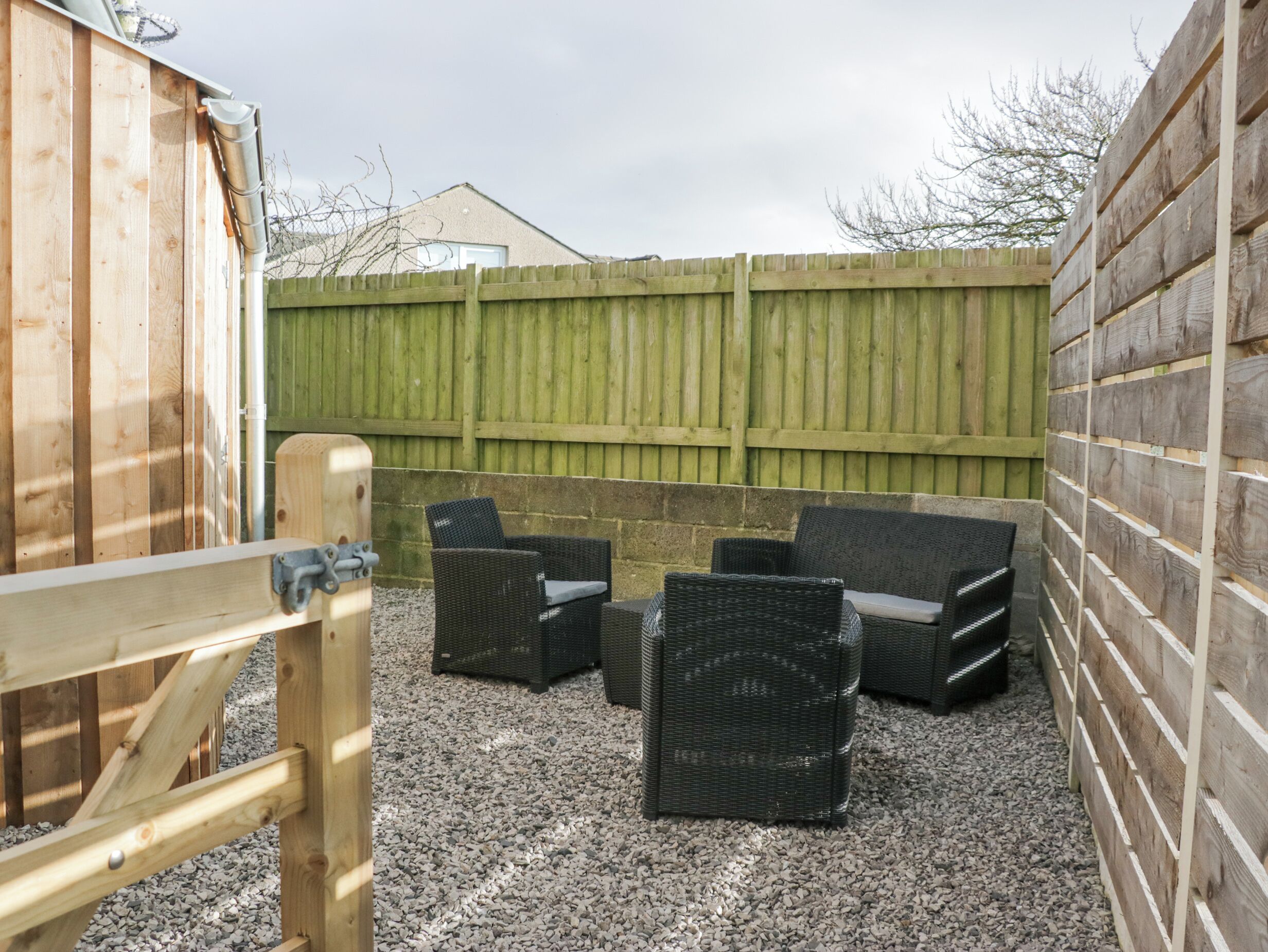 A patio area with wicker furniture and a wooden gate.