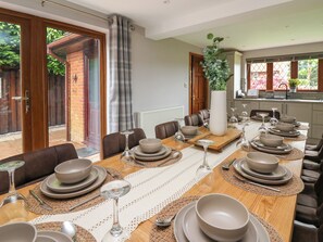 A dining area with a long wooden table set for a meal, surrounded by brown leather chairs. - Pondarosa (Llandrindod Wells)