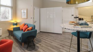 Un salon moderne avec un canapé de couleur turquoise, une table basse et un coin bar agrémenté d’un luminaire suspendu bleu.