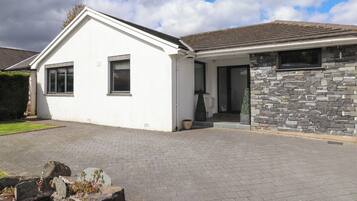 A single-story house with a white exterior, stone facade, and a paved driveway.