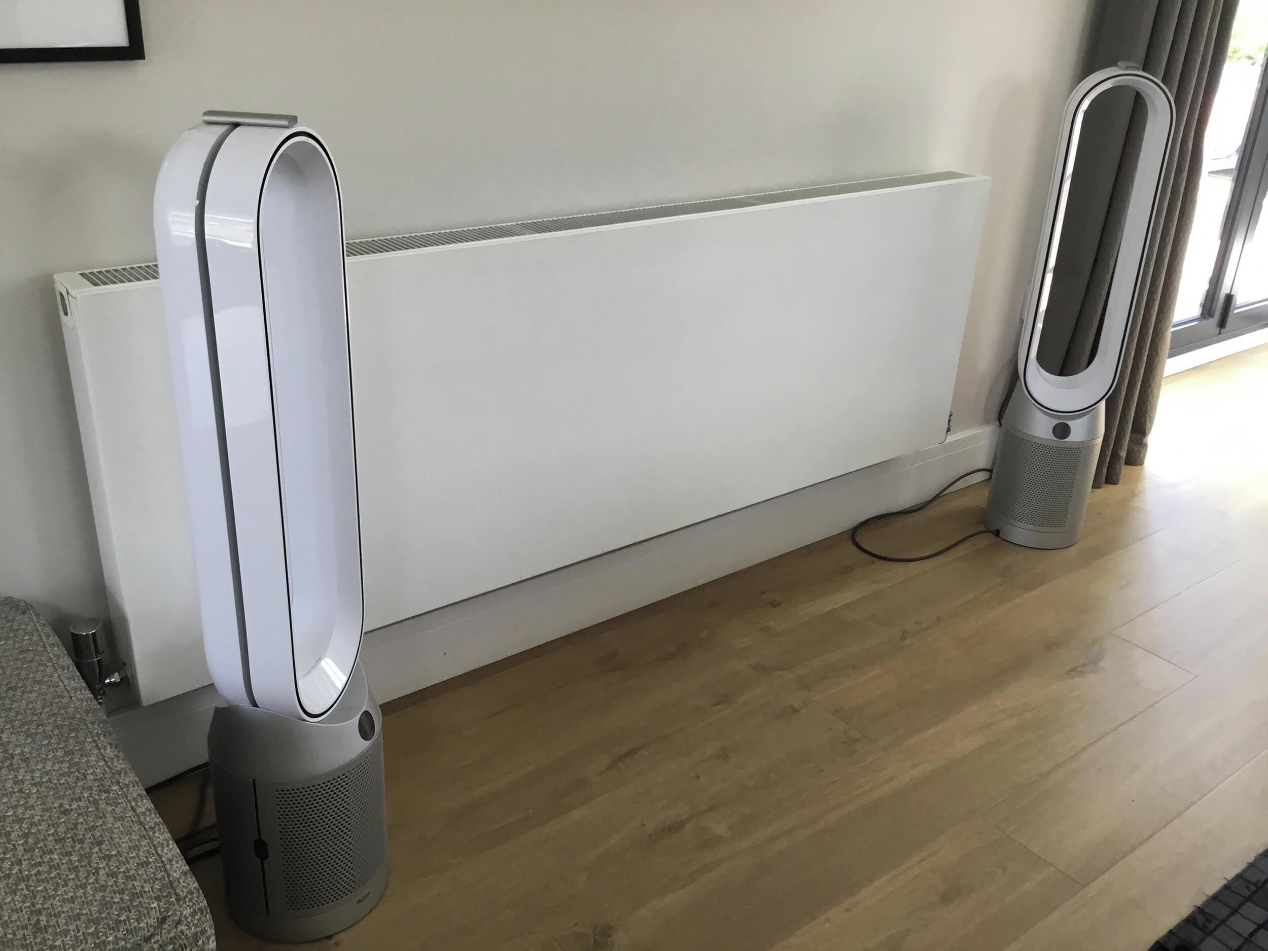 A room with a white radiator, a grey standing heater, and a grey floor.